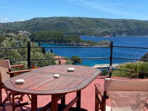 einen Holztisch auf einem Balkon mit Blick auf das Wasser in der Unterkunft Villa Stephanie in Paleokastritsa