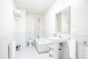 a white bathroom with a sink and a bath tub at Apartamentos GO - Único Sentido in Tordesillas