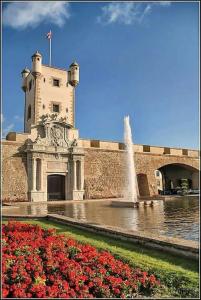 a building with a fountain and flowers in front of it at Apartamento La Perla Little Apartments in Cádiz