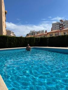 un hombre está sentado en una piscina en Apartamento Gasparot, en Villajoyosa