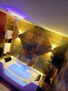 Una bañera en una habitación con una pared de piedra. en Les Charmes-Balnéothérapie-Vidéoprojecteur-Netflix, en Baume-les-Dames