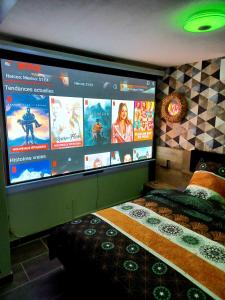Una pantalla grande en una habitación con cama en Les Charmes-Balnéothérapie-Vidéoprojecteur-Netflix, en Baume-les-Dames