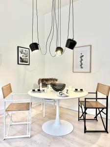 une salle à manger avec une table et des chaises blanches dans l'établissement MAKERS + ROOMS APARTMENTS, à Detmold