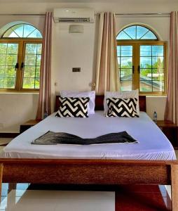 a bed in a room with two windows at The O.C Luxury Rooms in Kiembi Samaki