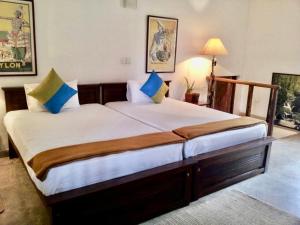 a bedroom with a large bed with blue pillows at Captain's Bungalow, Kandy in Arawwawala