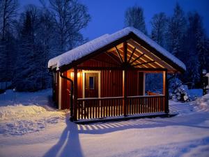 una piccola cabina nella neve di notte di Björkebostugan at the end of the road a Torsby