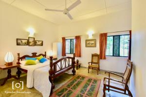 a bedroom with a bed and two chairs and windows at Captain's Bungalow, Kandy in Arawwawala