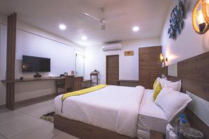 a bedroom with a bed and a desk with a television at Phoenix Resort in Rajkot