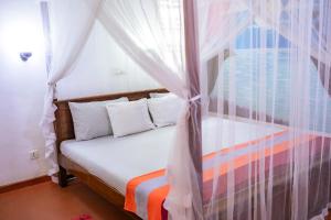 a bedroom with a bed with a canopy at Summer Lanka Surf House in Hikkaduwa