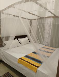 a white bed with a canopy and pillows at Villa kandupamula in Mirissa