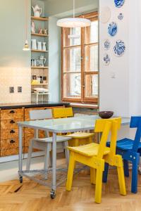 a kitchen with yellow and blue chairs and a table at Dymińska 10A by Homeprime in Warsaw