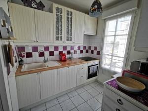 a kitchen with white cabinets and red and white tiles at Le Royal Condo, 13 P, WIFI & Parking à Disneyland in Chessy +24 photos