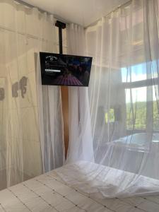 Schlafzimmer mit einem Bett und einem TV an der Wand in der Unterkunft Chalé Romântico Campina Grande do sul in Campina Grande do Sul