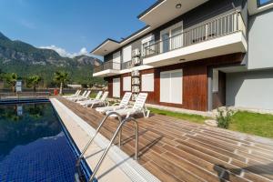 a deck with white chairs next to a swimming pool at Göynük Panorama Luxury Otel in Kemer