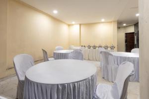 a room filled with tables and chairs with white tablecloths at Treebo Trend City Center in Nagpur