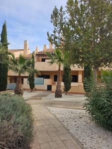 un edificio con palmeras delante en Private Apartment & Pool - El Oasis Golf Resort - Fuente del Alamo, en Murcia