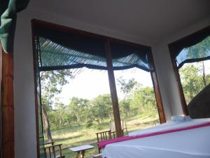 Schlafzimmer mit einem Fenster mit Blick auf ein Feld in der Unterkunft Doublegsafaris and camp mikumi in Mikumi