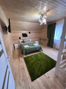ein Schlafzimmer mit einem grünen Bett und einem Kronleuchter in der Unterkunft Dva Braty eco in Podobovets
