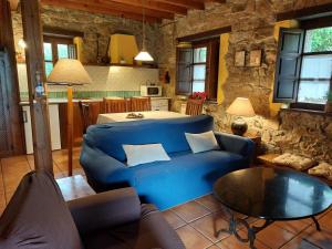 ein Wohnzimmer mit einem blauen Sofa und einem Tisch in der Unterkunft Casas rurales Valle de Bueida, jacuzzi en el El Palacio y Viscárcel in Bárzana