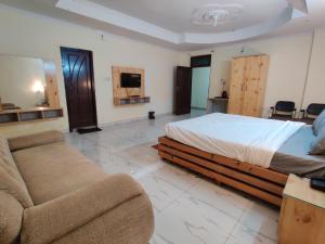 een slaapkamer met een bed, een bank en een tv bij HOTEL THE CORBETT VANSH in Rāmnagar