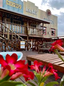 um edifício de banco com flores vermelhas em frente em Pousada Vila do Cowboy em Penha
