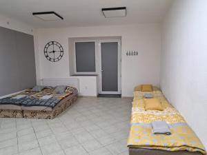 1 dormitorio con 2 camas y reloj en la pared en Apartmán NICOLAS en Brezno