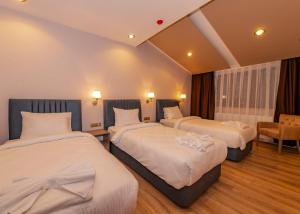 una habitación de hotel con 2 camas y una silla en IŞIL PARK HOTEL en Kars