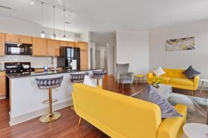a living room with a yellow couch and a kitchen at Affordable 2-Bedroom DT Detroit. in Detroit