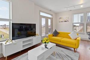 a living room with a yellow couch and a tv at Affordable 2-Bedroom DT Detroit. in Detroit
