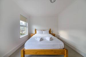 a bedroom with a bed with white sheets and a window at Pass the Keys - Spacious House with a Garden in Stratford, London in London