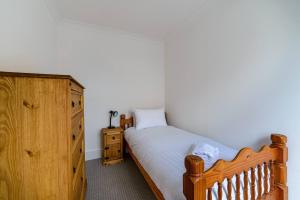 a bedroom with a wooden bed and a dresser at Pass the Keys - Spacious House with a Garden in Stratford, London in London