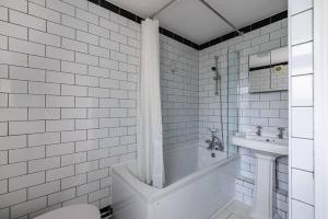 a white bathroom with a tub and a sink at Pass the Keys - Spacious House with a Garden in Stratford, London in London