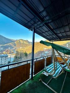 a chair sitting on a balcony with an umbrella at Woodland Borjomi in Borjomi