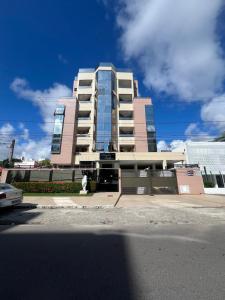 um edifício alto numa rua em frente a um edifício em FlatSuíte Cabo Branco 2Quartos Almeida em João Pessoa
