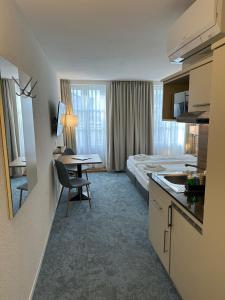 a hotel room with a bed and a kitchen and a desk at Aparthotel Krone - Self Check-In in Interlaken