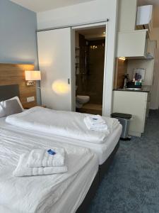 2 letti in camera d'albergo con asciugamani di Aparthotel Krone - Self Check-In a Interlaken