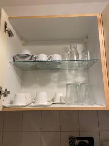 a shelf with plates and cups and glasses on it at In Saarbrücken Stadtnahe gemütliche Wohnung am Deutsch-Französischen Garten in Saarbrücken +31 photos