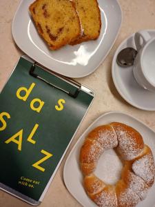 dos platos de comida con un libro y un plato de pan en Boutique Hotel das Salz, en Salzburgo