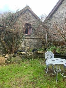 a table and chair in front of a stone building at Games Room in Llanfynydd