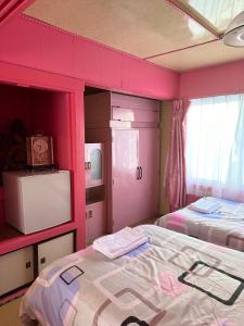 a room with two beds and a pink wall at 水雲間民宿 in Furano