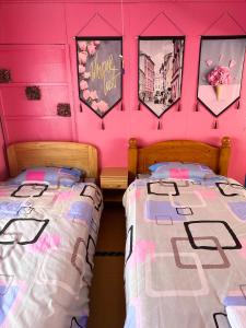 two beds in a room with pink walls at 水雲間民宿 in Furano