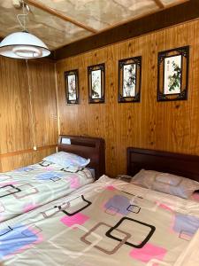 two beds in a room with wooden walls and windows at 水雲間民宿 in Furano
