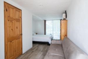 a room with a couch and a bed and a window at Hotel Bamboo in Jacó