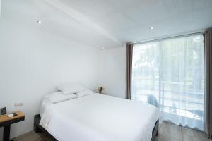 a bedroom with a white bed and a large window at Hotel Bamboo in Jacó