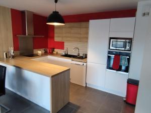 - une cuisine avec des murs rouges, des placards blancs et un évier dans l'établissement Beau T3 + clim + parking Saint Cyr sur mer, à Saint-Cyr-sur-Mer