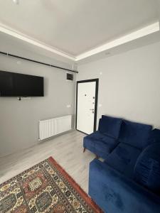 a living room with a blue couch and a flat screen tv at 6 şubat apartmanı in Avanos