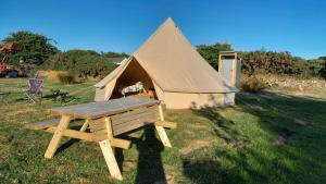 Tienda de campaña con mesa de picnic de madera en un campo en Cornish Skies Glamping, en Pool