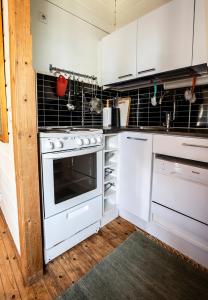 eine Küche mit weißen Geräten und schwarzen Fliesen in der Unterkunft Lomariihi 2 in Muurame