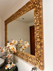 a mirror with a wooden frame and flowers in a bathroom at Hotel Bamboo in Jacó