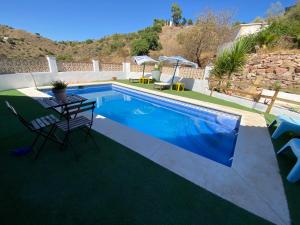 a swimming pool with a table and chairs next to it at Casa Rural Los Almendros in Málaga